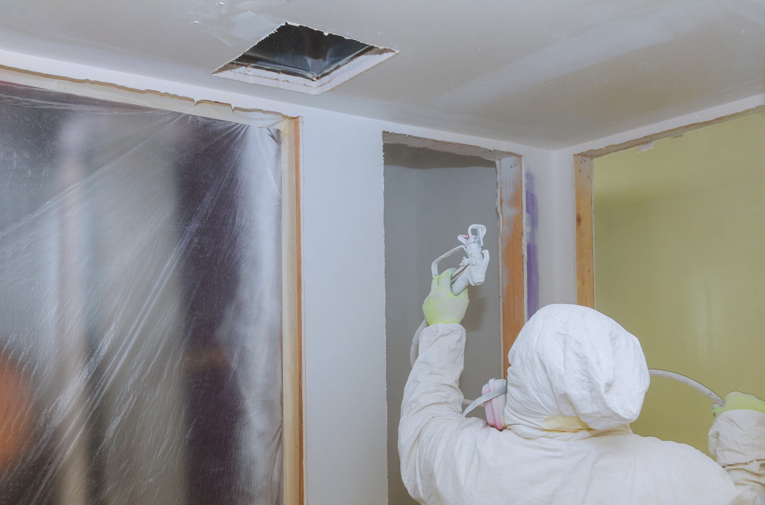 Worker painting wall with spray gun in white color hand the tool the spray of paint